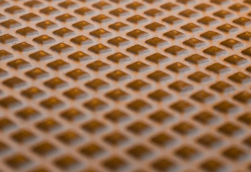 A close view of a fine perforated metal mesh panel of the kind fitted over the top of a gutter.